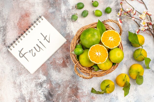 Top view fresh mandarines in wicker basket mandarines feykhoas fruit written on notepad on nude background