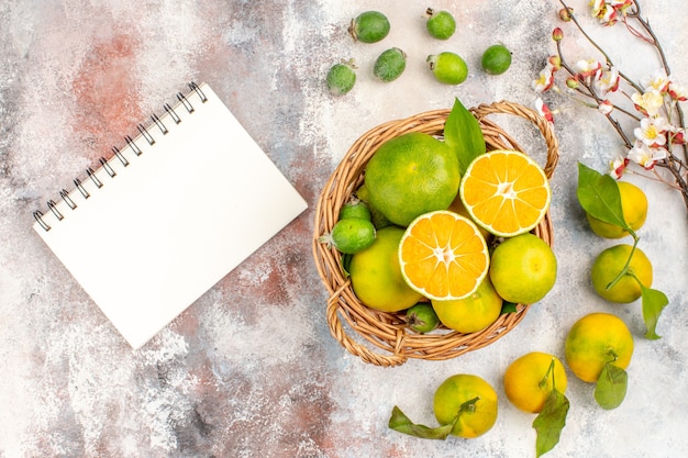 Top view fresh mandarines in wicker basket mandarines feykhoas a notebook on nude background