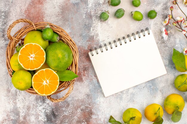 Top view fresh mandarines in wicker basket mandarines feykhoas notepad on nude background