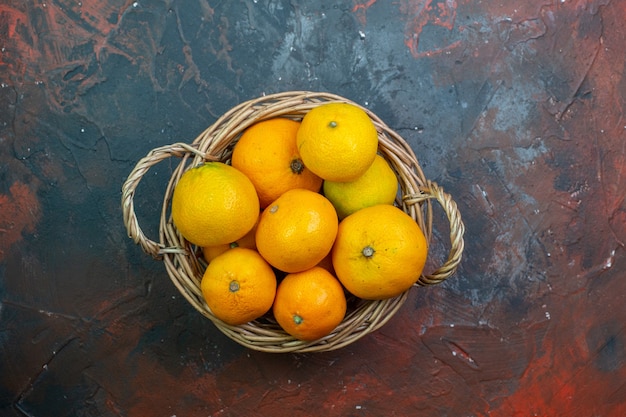 Top view fresh mandarins in basket on dark red background