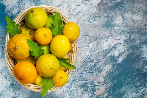 Top view fresh mandarins on wicker basket on blue white surface copy place