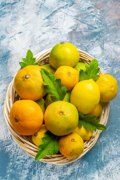 Free photo top view fresh mandarins on wicker basket on blue white surface