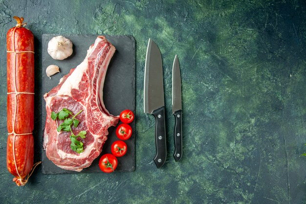 紺色の背景にソーセージを添えた新鮮な肉のスライスの上面図肉キッチン動物牛料理肉屋チキンカラー