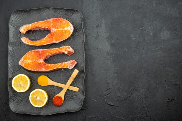 Top view fresh meat slices inside plate with lemon slices on dark background