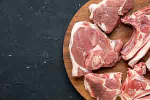無料写真 上面図新鮮な肉は、暗い食品の鮮度の動物の牛の食品のキッチンの丸い木製の机の上に生肉をスライスします