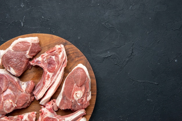 Бесплатное фото Вид сверху на ломтики свежего мяса сырое мясо на круглом деревянном столе на темной кухне свежесть коровьей еды