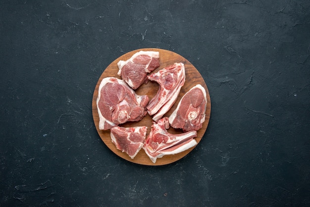 Вид сверху на ломтики свежего мяса сырое мясо на круглом деревянном столе на темной еде свежесть животная коровья еда еда кухня