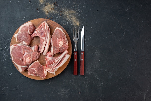 Top view fresh meat slices raw meat with fork and knife on dark kitchen salad meal food cow food animal dish