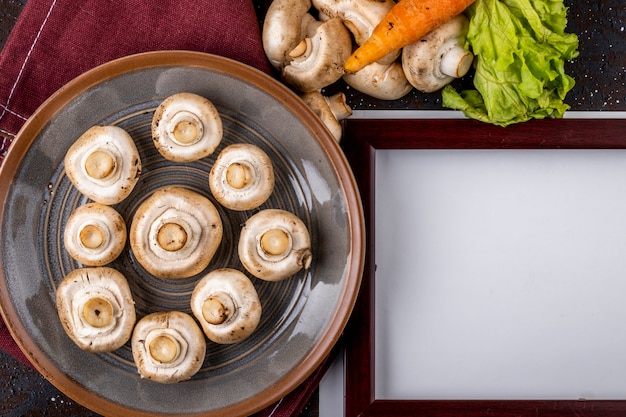 Вид сверху шампиньонов свежих грибов на керамической тарелке на столе