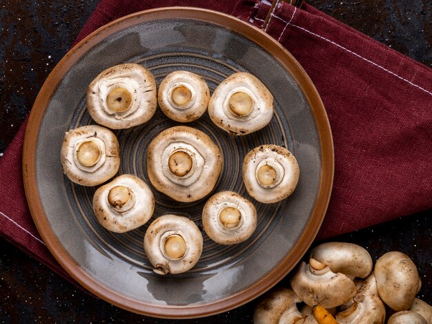 Top view of fresh mushrooms champignon on ceramic plate on the table