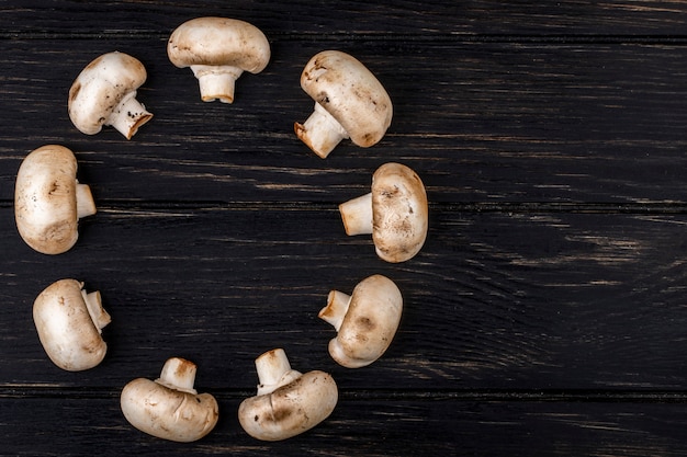 Top view of fresh mushrooms champignon on dark wooden background with copy space