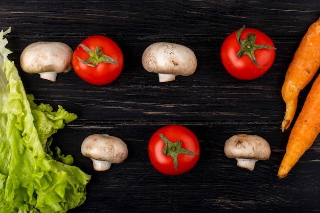 Top view of fresh mushrooms champignon and tomatoes with carrot on dark wooden background