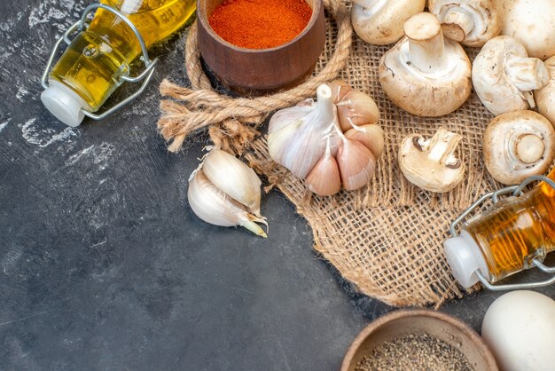 Top view fresh mushrooms eggs oil bottle red pepper powder in small bowl garlic on grey table copy place