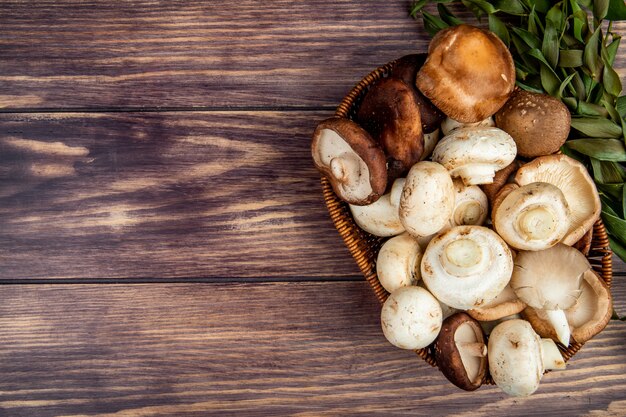 Top view of fresh mushrooms in a wicker basket on rustic wood with copy space