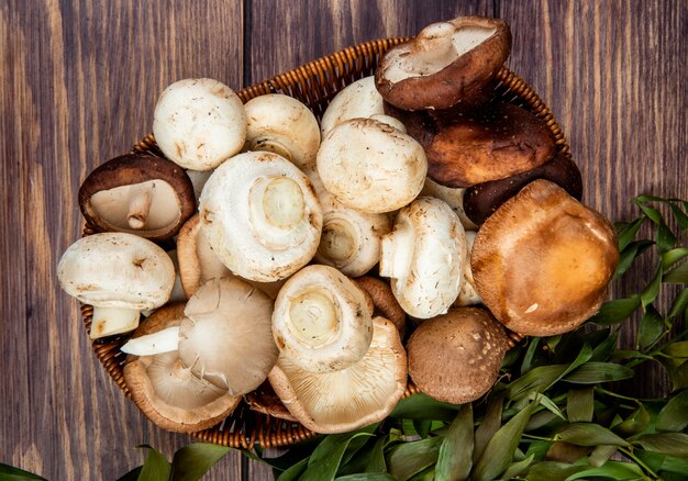 Top view of fresh mushrooms in a wicker basket on rustic wood