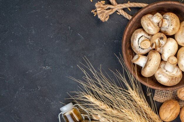 Top view fresh mushrooms in wooden bowl walnuts on table with copy place