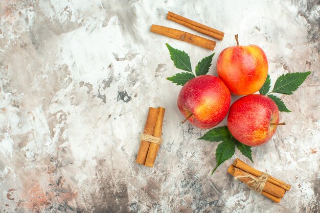 Top view of fresh natural red apples and cinnamon limes on the left side on mixed color background