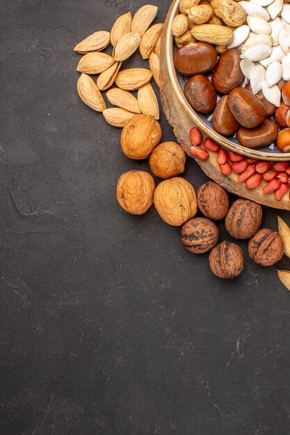 Top view of fresh nuts peanuts and other nuts on dark surface