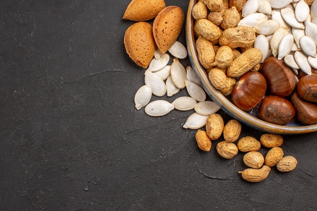 Top view of fresh nuts peanuts and other nuts on dark surface