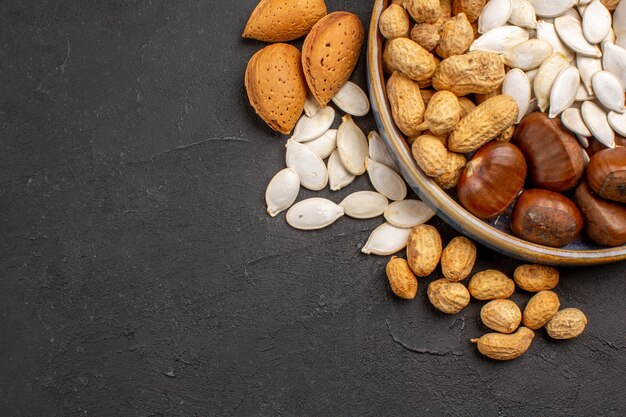 Top view of fresh nuts peanuts and other nuts on dark surface