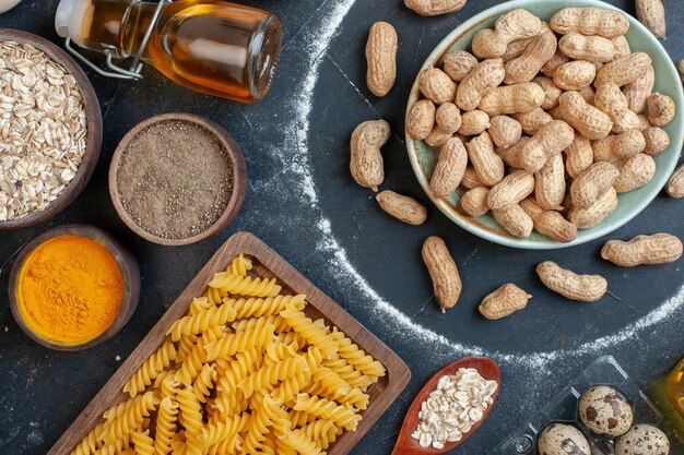 Top view fresh nuts with raw pasta seasonings and eggs on a dark background color food meal nut snack egg milk dough