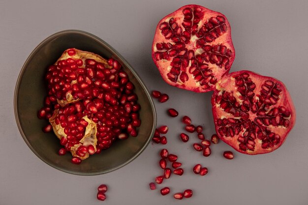 Top view of fresh open pomegranates on a bowl with halved pomegranates isolated