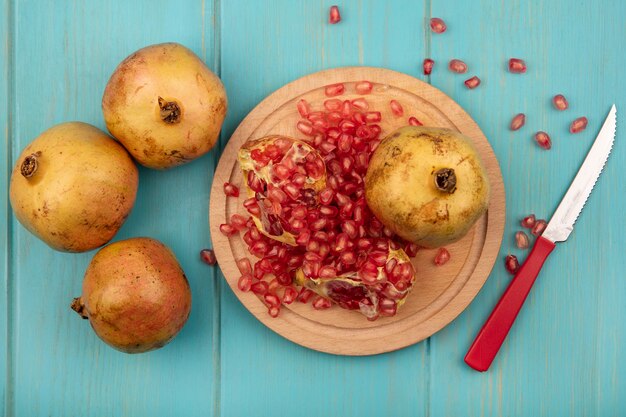 Top view of fresh open pomegranates with seeds isolated on a wooden kitchen board with knife on a blue wooden surface