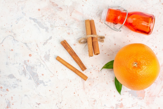 Top view fresh orange cinnamon sticks bottle on bright surface with copy space