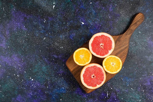 Top view of fresh orange and grapefruit slices on wooden board.