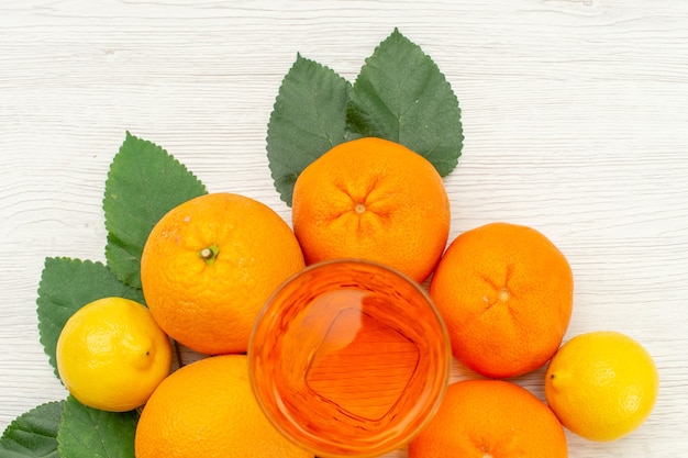 Top view fresh orange juice with oranges and citruses on light white surface citrus exotic tropical fruit juice