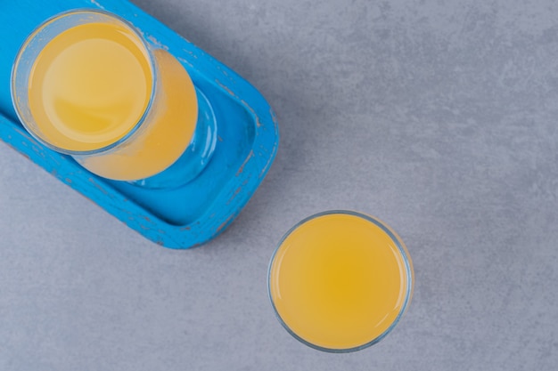 Top view of fresh orange juices on blue wooden board