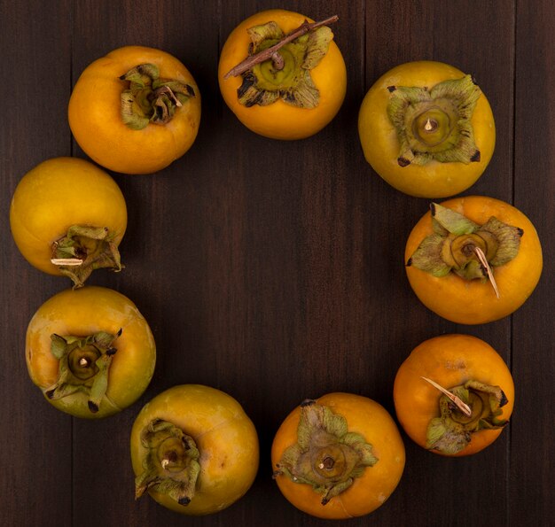 Top view of fresh orange organic persimmon fruits with leaves isolated on a wooden table with copy space