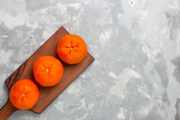 Top view fresh orange tangerines whole sour and mellow citruses on the light white background.