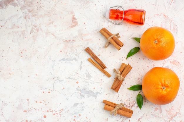 Top view fresh oranges cinnamon sticks bottle on bright surface free space