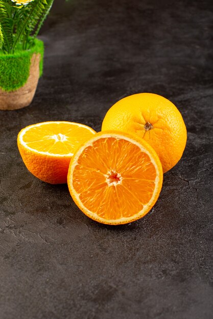 Вид сверху свежие апельсины кислые спелые целые и нарезанный мягкий цитрусовый тропический витаминно-желтый на темном столе