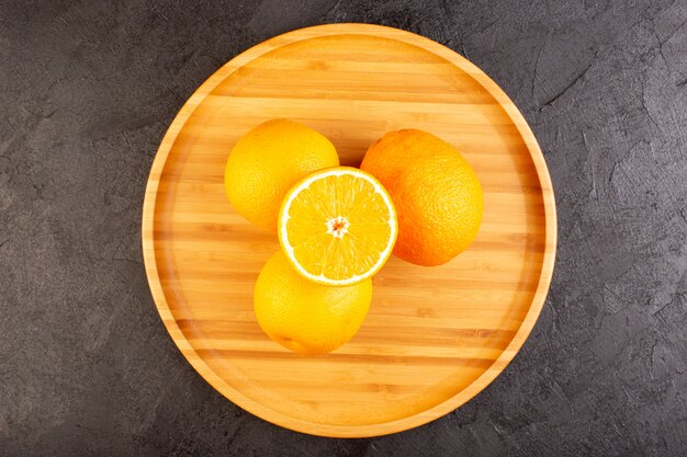 상위 뷰 신선한 오렌지 신은 잘 익은 전체와 얇게 썬 부드러운 감귤 열대 비타민 노란색 어두운 책상에