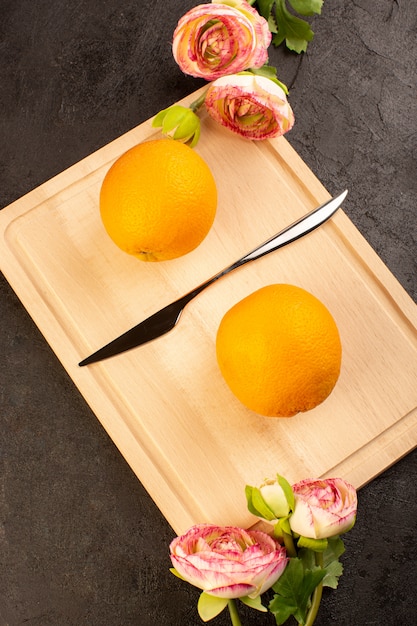 Foto gratuita una vista dall'alto arance fresche acide mature intere con rose secche agrumato dolce tropicale vitamina giallo sulla scrivania scura