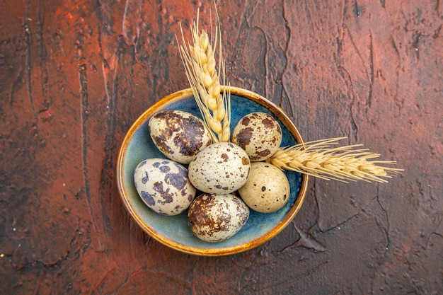 Top view of fresh organic poultry farm eggs inside and outside of blue plate on a brown background