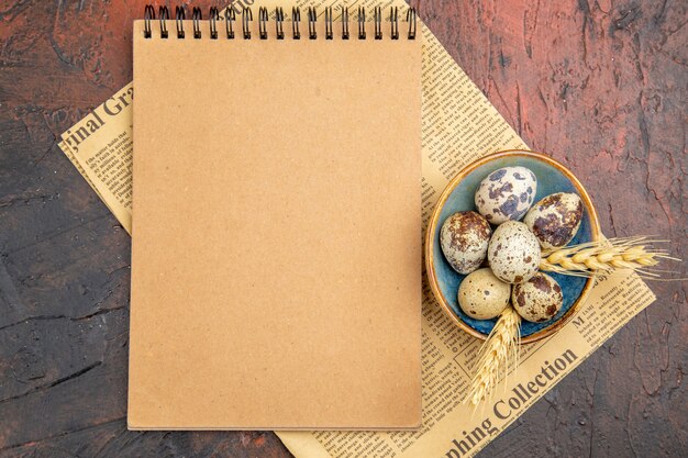 Top view of fresh organic poultry farm eggs inside and outside of blue plate on an old newspaper a notebook on a brown background