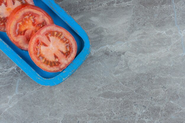 Top view of fresh organic tomato slices on wooden plate. 