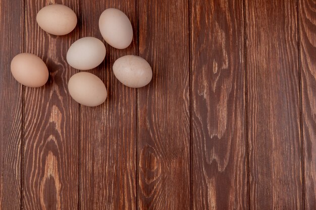 Вид сверху на свежие яйца овальной формы на деревянном фоне с копией пространства