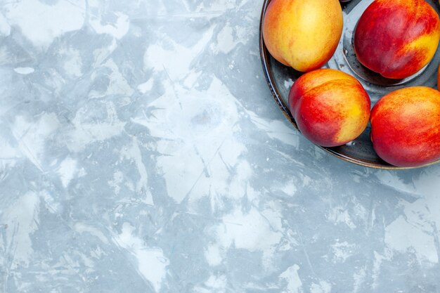 Top view fresh peaches delicious summer fruits on the light-white desk