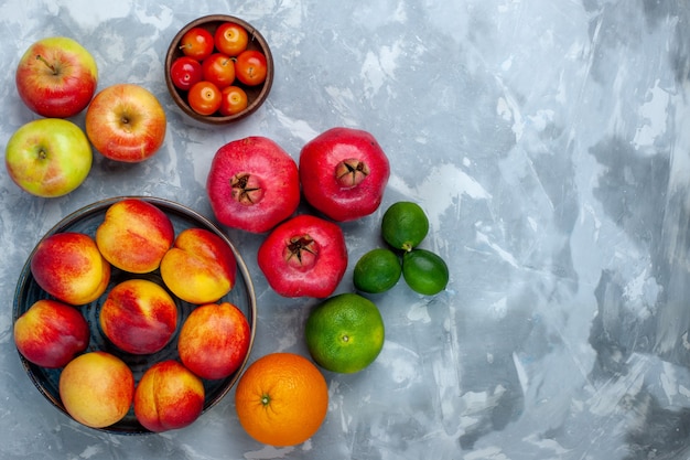 Top view fresh peaches delicious summer fruits with plums and apples on light-white desk