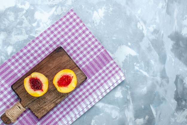 Вид сверху свежие персики, спелые и вкусные фрукты, нарезанные на светло-белой поверхности