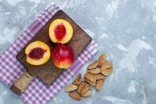 Top view fresh peaches mellow and tasty fruits with nuts on light-white desk