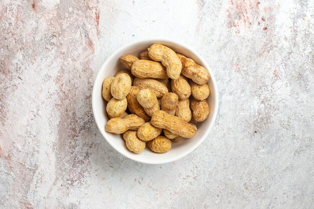 Top view of fresh peanuts inside plate on white surface