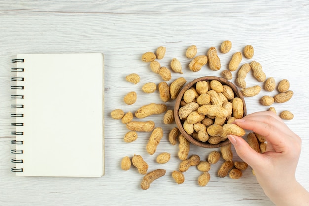 Top view fresh peanuts with notepad on white tabl