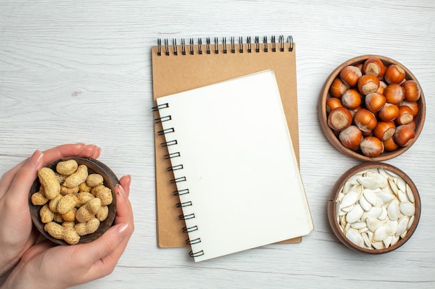 Top view fresh peanuts with white seeds and hazelnuts on white table