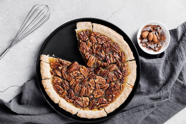 Top view fresh pecan pie and whisk on the table