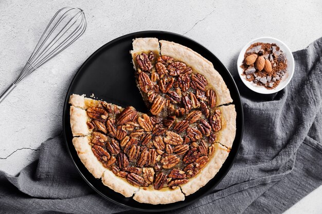 Top view fresh pecan pie and whisk on the table